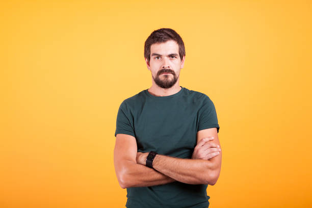 Grumpy stressed worried man on yellow background lookin at the camera