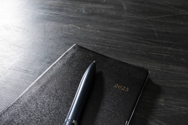 istock 2025 Notebook and pen on wooden table (2025 schedule book) 2180219389