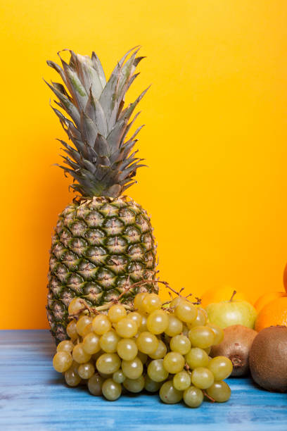 Pineapple, grapes and other fruits on yellow background. Various fruits