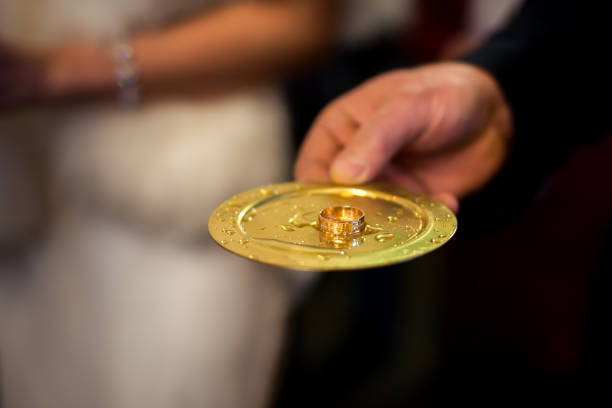 The groom places a ring on the bride's finger, capturing the hands of the newlyweds on their wedding day in close-up