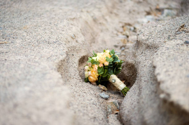 Wedding bouquet and champagne bottle in the sand.