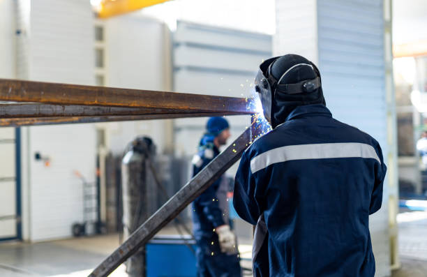istock Man welds metal pipe at construction site. 2180222613