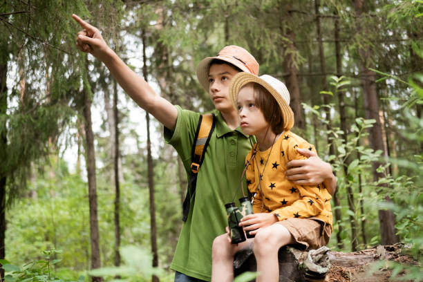 istock Boy Scouts explore the forest. A teenage boy points his hand at something interesting to a little boy. 2180223246