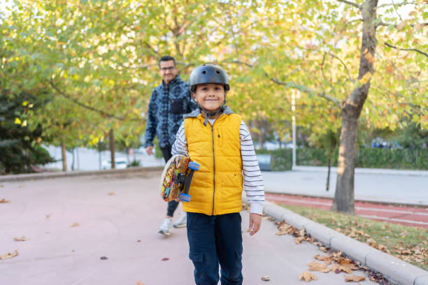Father Helping Son To Ride On Skateboard At A Skate Park