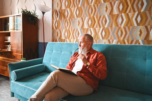 istock Senior man reading book at home. 2180225187