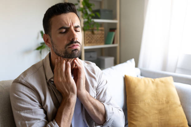 istock Man suffering from sore throat touching neck feeling pain. Copy space. 2180229994