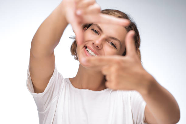 istock Smiling Woman Framing Her Face with Hands in Creative Gesture 2180232121