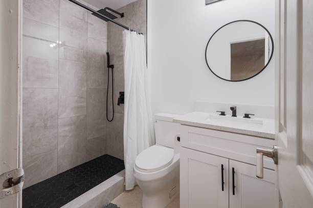 istock Modern bathroom with a walk-in shower, white vanity, and round mirror 2180232878