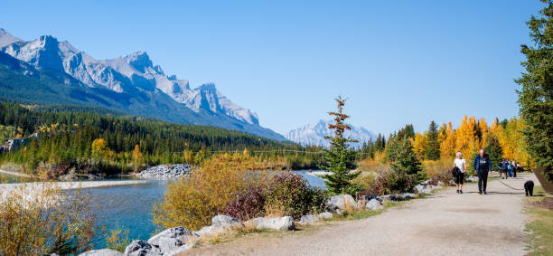 Canmore, Alberta, Canada - October 1 2022 : People walking along the Bow River riverside trail in autumn. Rundle Plante Lane.