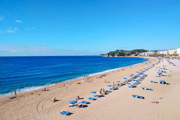 istock Sunny Beach Day on Mediterranean Coast with Blue Umbrellas and Clear Sky 2180237795