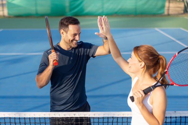 istock Smiling tennis players high-five over net after friendly game 2180238533
