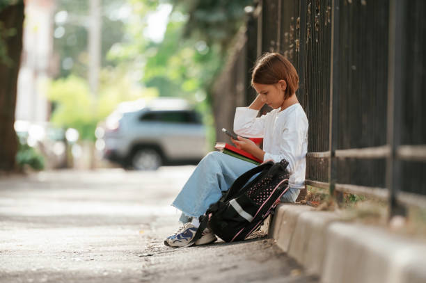 istock On the sidewalk. Schoolgirl with backpack is outdoors 2180243565