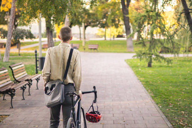 istock Smiling businessman commuter is enjoying at public park on his bicycle trip from work after a long workday. Sustainable concept of going to work by bicycle. 2180244864