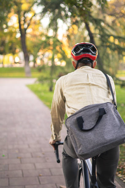 istock Smiling businessman commuter is enjoying at public park on his bicycle trip from work after a long workday. Sustainable concept of going to work by bicycle. 2180245708