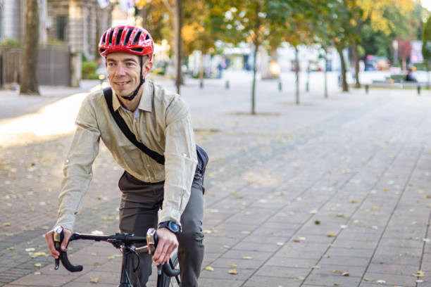 istock Smiling businessman commuter is enjoying at public park on his bicycle trip from work after a long workday. Sustainable concept of going to work by bicycle. 2180247271
