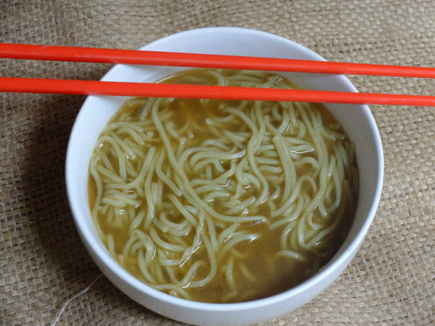 instant noodle soup in a white ceramic bowl. red chopsticks.