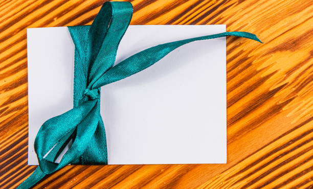 Blank note with green ribbon left on wooden board, concept High quality photo