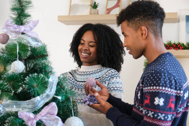 istock Young couple decorating Christmas tree with ornaments at home 2180256463