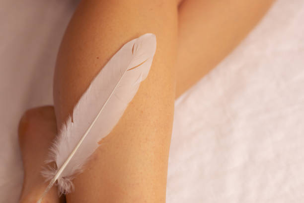 istock A person gently touches a soft feather against their leg in a serene indoor setting 2180257011