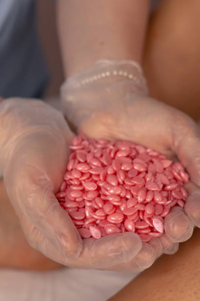 istock Pouring pink wax beads into gloved hands for a waxing procedure in a salon setting 2180257096