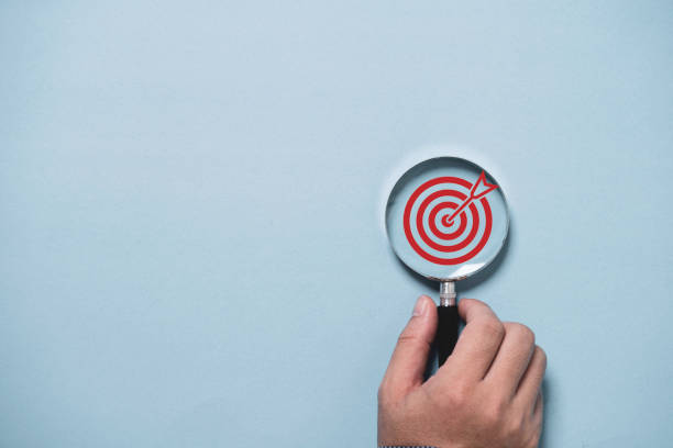 istock Hand holding target board inside of magnifier glass for focus business objective on blue background and copy space. 2180257539