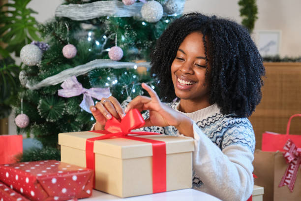 istock Woman wrapping Christmas presents under the tree is smiling 2180259982