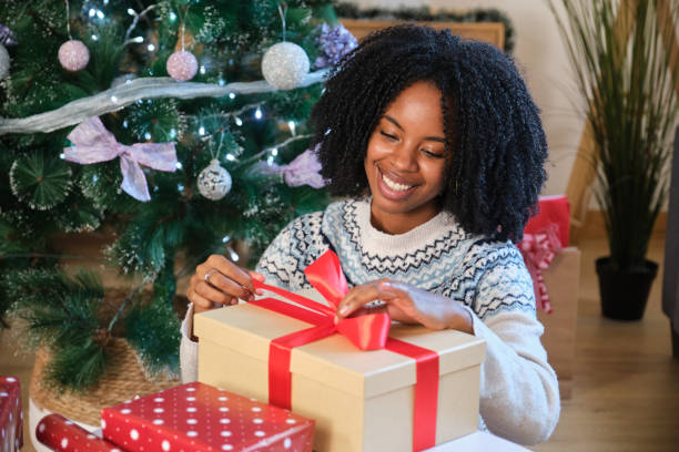 istock Woman wrapping Christmas presents under the tree is smiling 2180260054