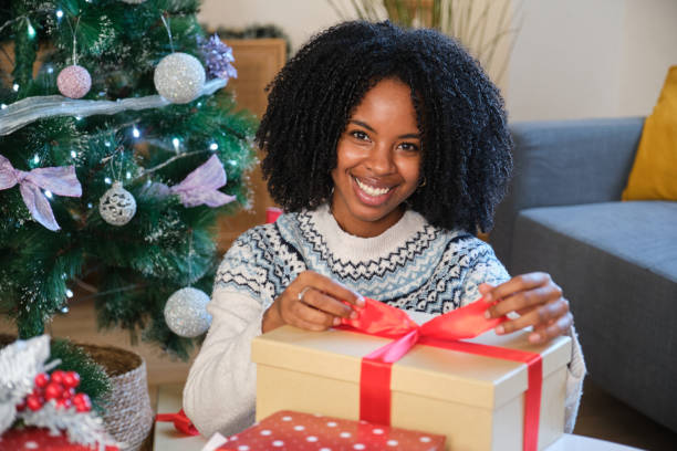 istock Woman wrapping Christmas present smiling at home 2180260122