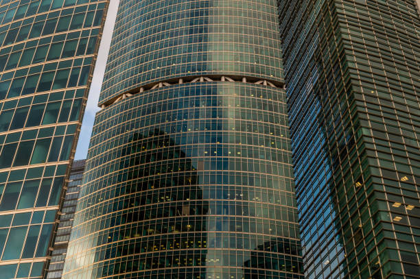 Angled view of modern skyscrapers in business district against blue sky. Looking Up high-rise office buildings. Evening time, sunset. Orange, yellow and gold shades of color.