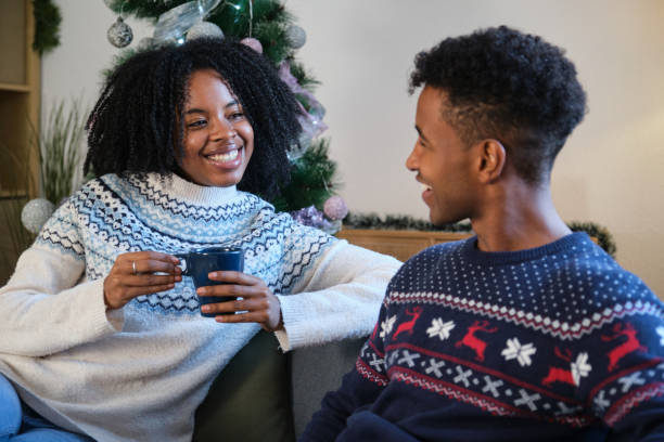 istock Young couple wearing Christmas sweaters enjoying hot drinks at home 2180263096