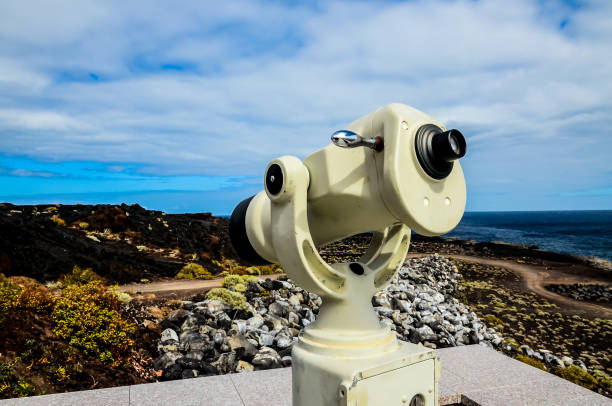 istock A telescope is mounted on a pole in front of a rocky shoreline 2180264456