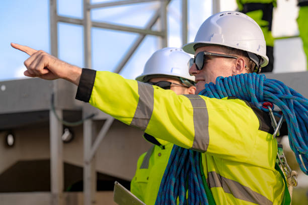 istock Two engineers in safety helmets and high visibility jackets engage in a field inspection. One is pointing while carrying a safety rope, highlighting communication, safety, and teamwork. 2180265514