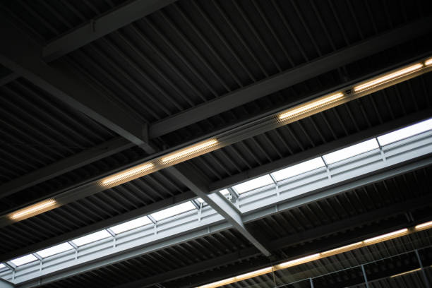 istock Warehouse hall with ceiling lighting. Corrugated metal sheet ceiling and skylight window. Industrial building with metal texture and overhead lighting. 2180267612