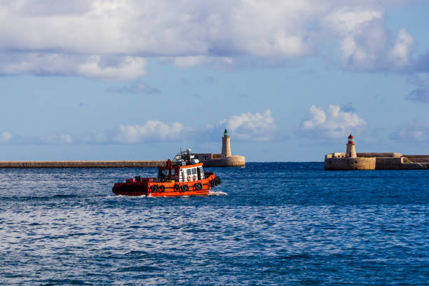 Orange Tugboat Navigating Between Two Ancient Lighthouses