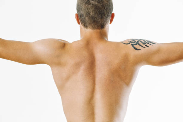 Shirtless man standing in a meditative posture with eyes closed, hands in a mudra position, and facing a large window in a calm studio. The soft natural light and minimal setting create an atmosphere of inner peace, mindfulness, and spiritual focus