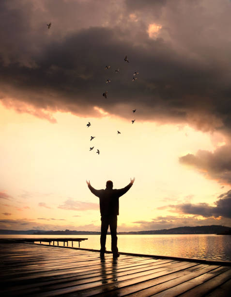 Single man on wooden pier looking at seascape during sunrise