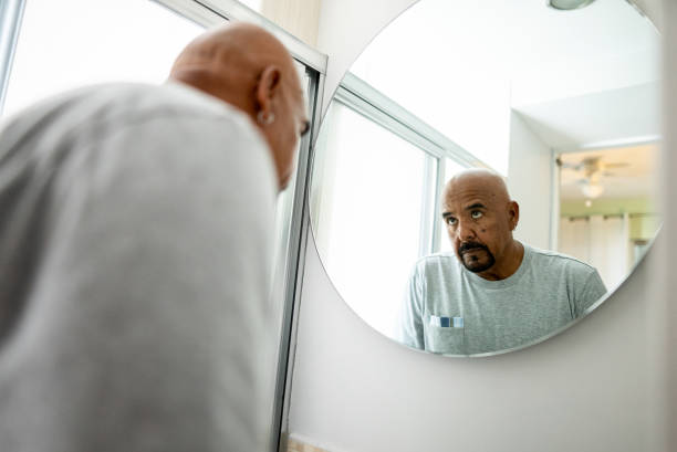 istock Worried senior man looking in the mirror at home 2180287309