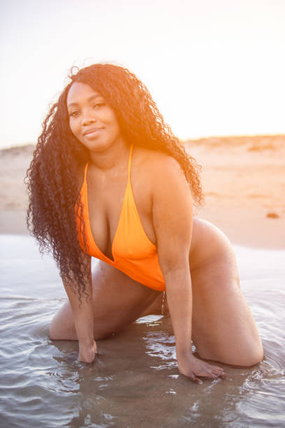 istock African American Radiant plus-size model embraces sunset on beach, radiating confidence and embody body positivity and glamour in beautiful summer moment 2180287549
