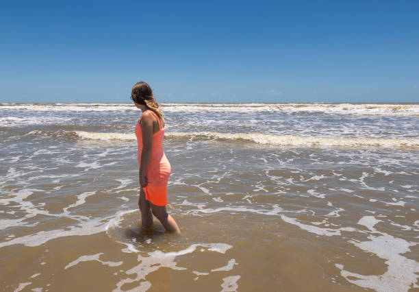 Young woman wading  in the surf  on the beach at Jamacia Beach, Texas, USA