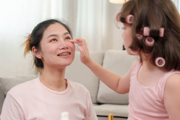 istock Young girl gently applying makeup to smiling mother with joyful expression while engaging in a playful, loving bonding moment during a makeup session. Warm, affectionate family moment showing care. 2180290267