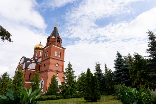 istock A significantly large red brick building, which features a prominent bell tower, is beautifully surrounded by lush green trees, creating a harmonious scene in the natural landscape 2180291321
