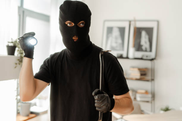 istock Masked burglar holding crowbar and flashlight is about to commit crime 2180294083