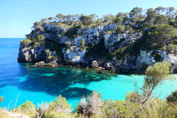 istock Panoramic view of the beaches of Macarella and Macarelleta. This remote bay has high cliffs covered in pine-trees which drop down to pale white sand and crystal-clear water. Paradisiacal beaches with turquoise waters. Island of Menorca. Balearic Islands 2180296154