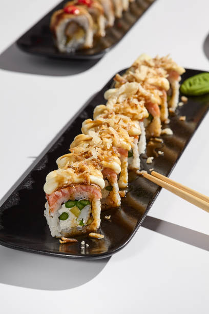 Delicious Asparagus Mango Roll with Torched Salmon and Truffle Sauce on Elegant Black Plate under Bright Lighting