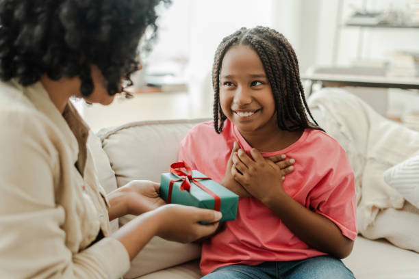 istock Mother giving present to daughter sitting on sofa at home 2180298526