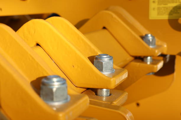 Detailed view of yellow machinery components with nuts and bolts, showcasing intricate industrial design