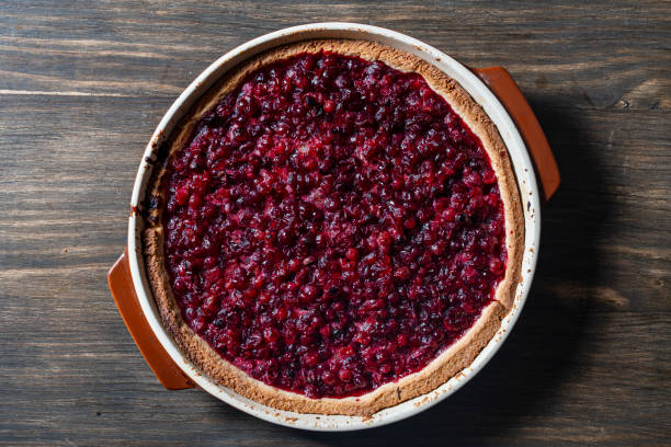 istock Delicious autumn pie on shortcrust pastry with red cranberries on a table. Cranberry cake with jam and sugar in a baking dish, rustic style, closeup, top view 2180299859