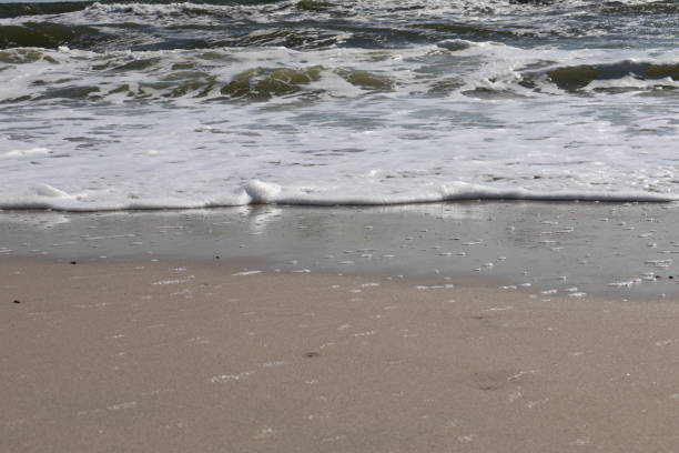 istock Gentle Ocean Waves Washing Over Smooth Sandy Beach under Clear Blue Sky 2180299875