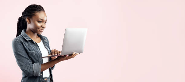 istock Black Student Lady Holding Laptop Computer Standing On Pink Background 2180300190