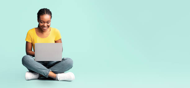 istock Happy Black Lady Using Laptop Sitting Over Blue Background, Panorama 2180300235
